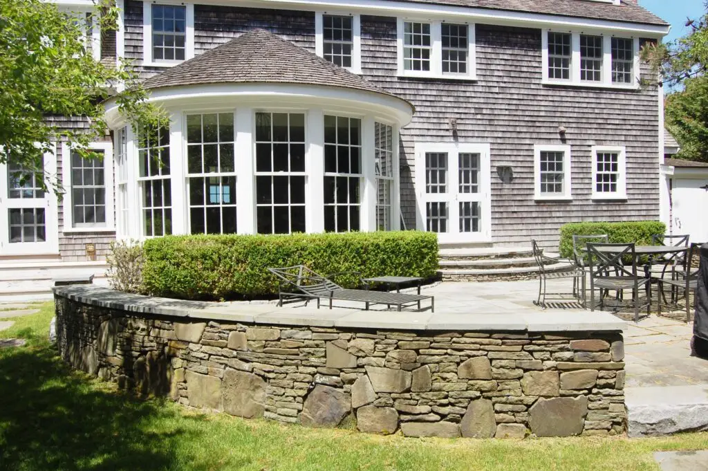 A walled patio carved out of the wood and drawn to reflect the curves and planes of the historic house.